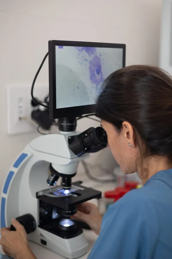 Pathology scientist reviewing a sample under a microscope