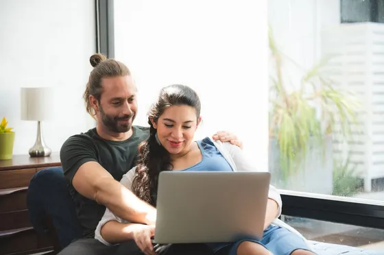 Couple smiling at a laptop together at home