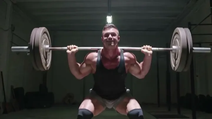 Man doing a barbell squat in a gym