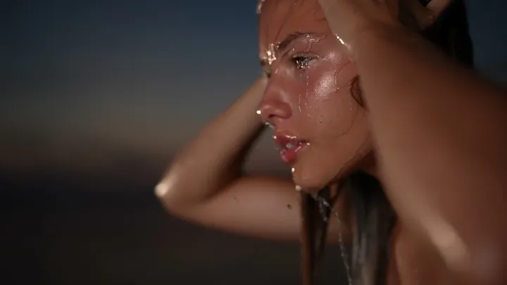 Woman with water on her face at dusk