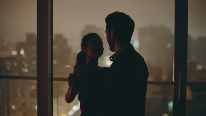 Couple standing by a window above city lights