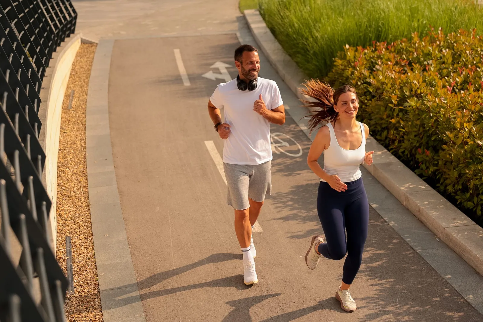 Smiling couple running together on a sunny city path